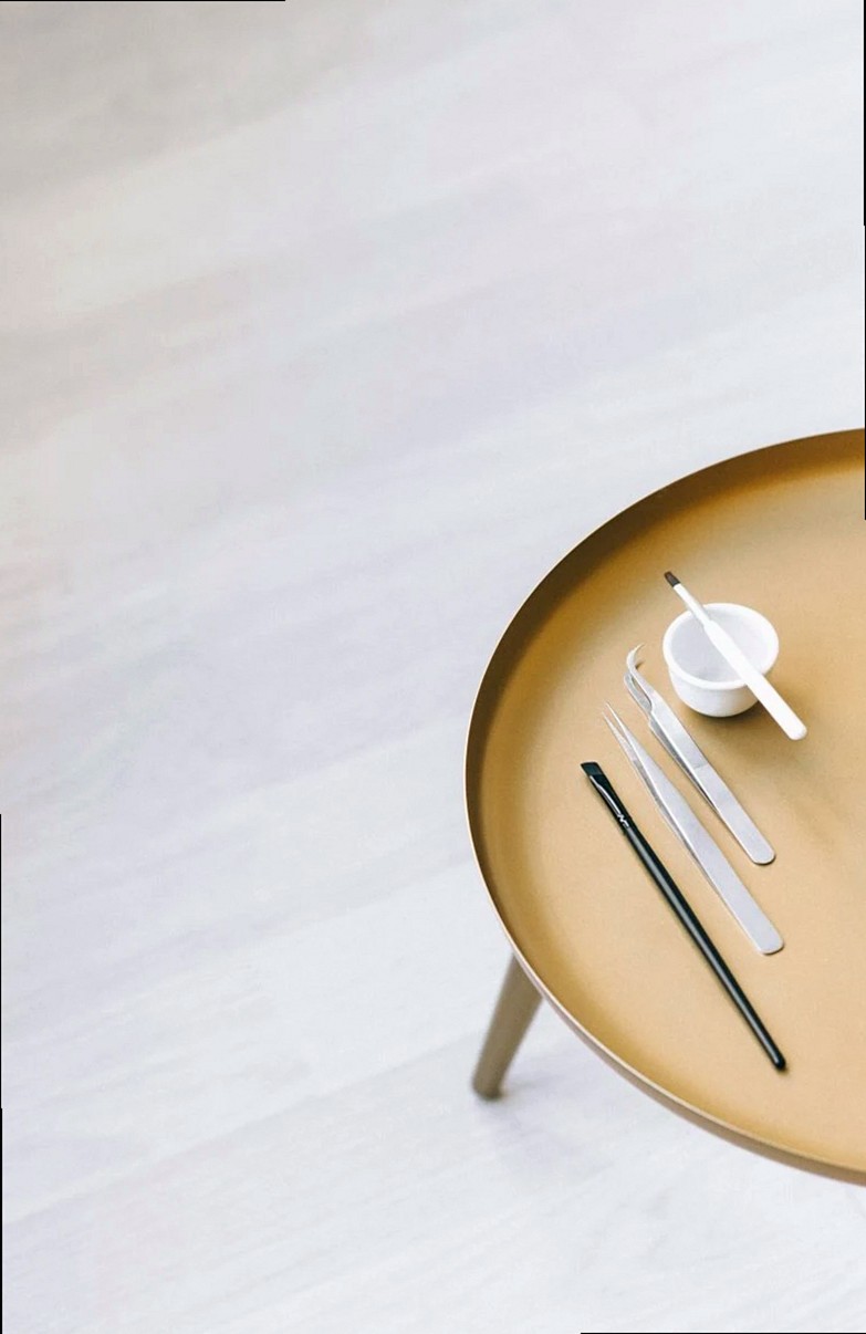 Diseño minimalista de mesa que muestra pinzas cosméticas sobre una elegante mesa redonda.