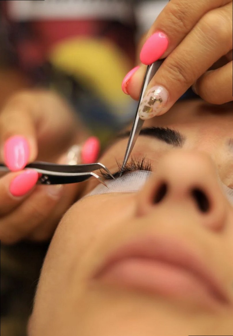 Primer plano detallado de la aplicación de extensiones de pestañas en un salón de belleza.
